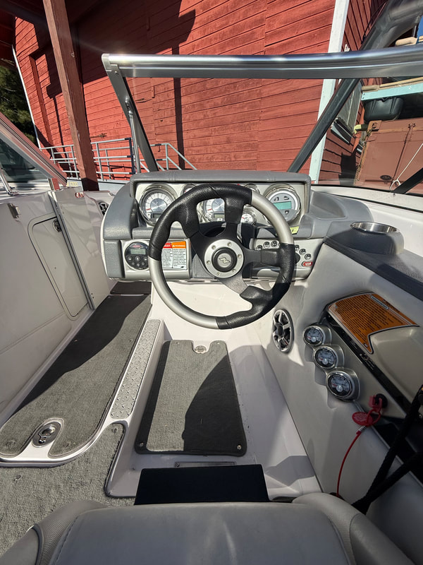 Close-up of helm, throttle controls, and captain’s seat